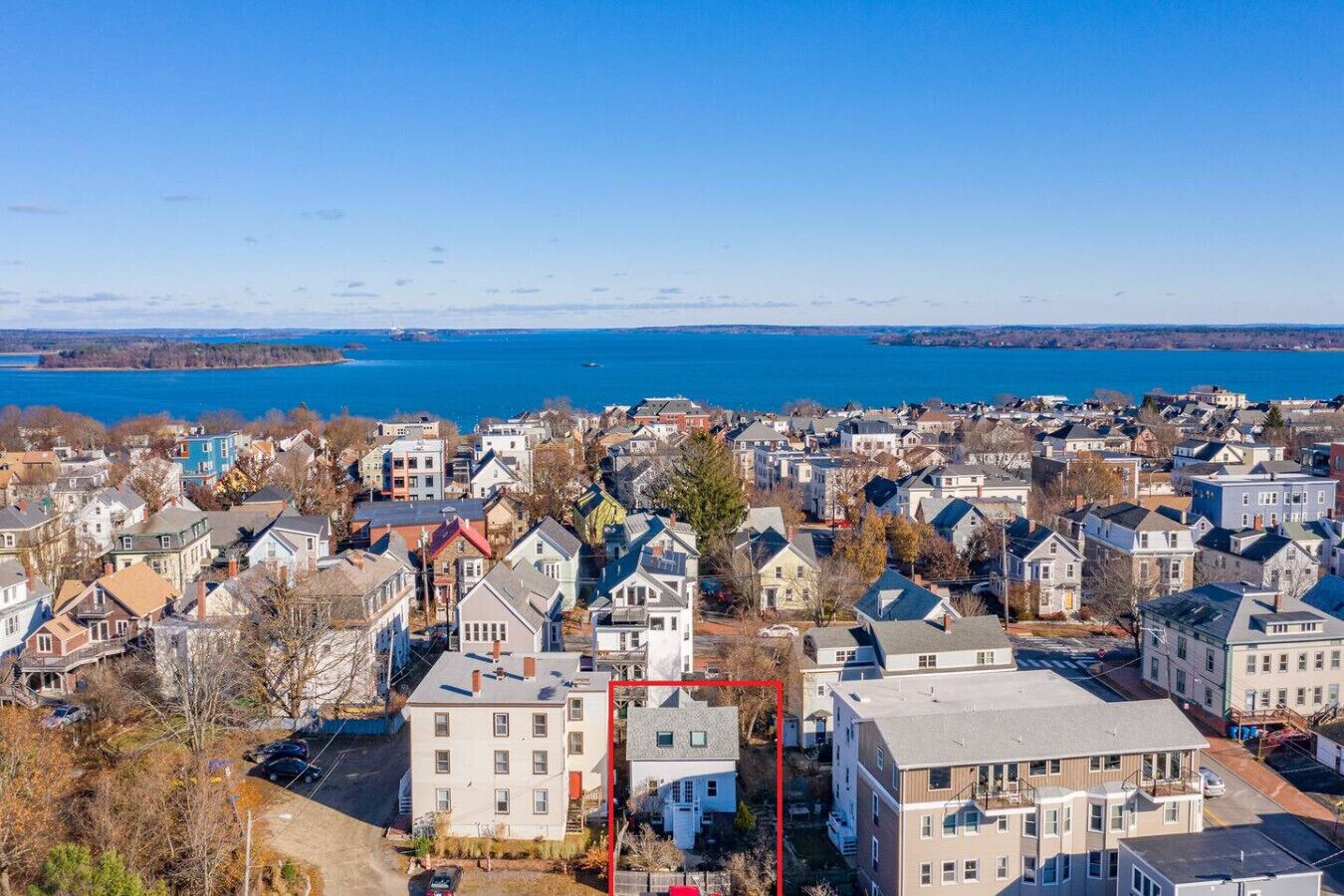 A residential area with houses, a clear blue sky, and a lake in the background.