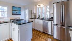 Una cocina moderna con armarios blancos, electrodomésticos de acero inoxidable y suelo de madera.