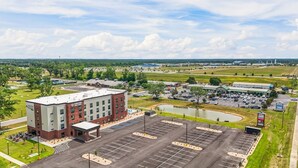 A hotel with a parking lot, a small pond, and a bridge in the background.