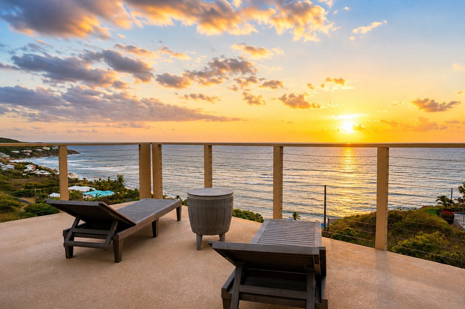 Een zonsondergang uitzicht vanaf een balkon met twee loungestoelen en een ronde tafel.