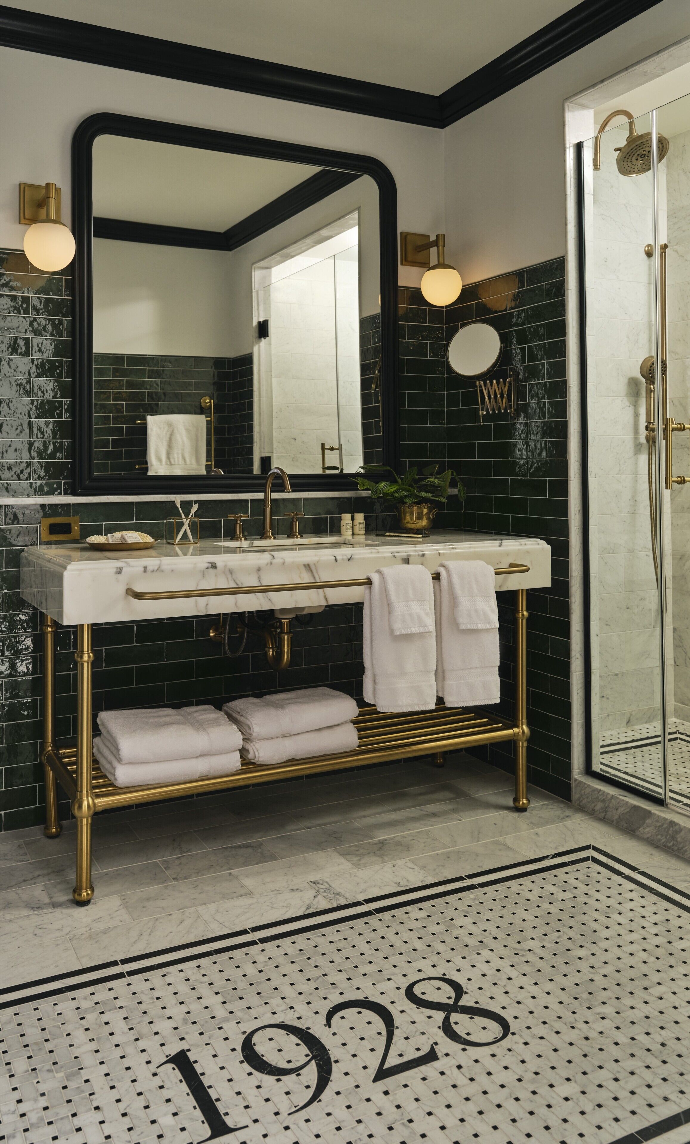 A bathroom with a white marble sink, gold fixtures, a large mirror, and a black and white tiled floor.