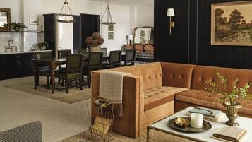 A spacious living room with a brown sofa, a coffee table, and a dining area with chairs and a table.