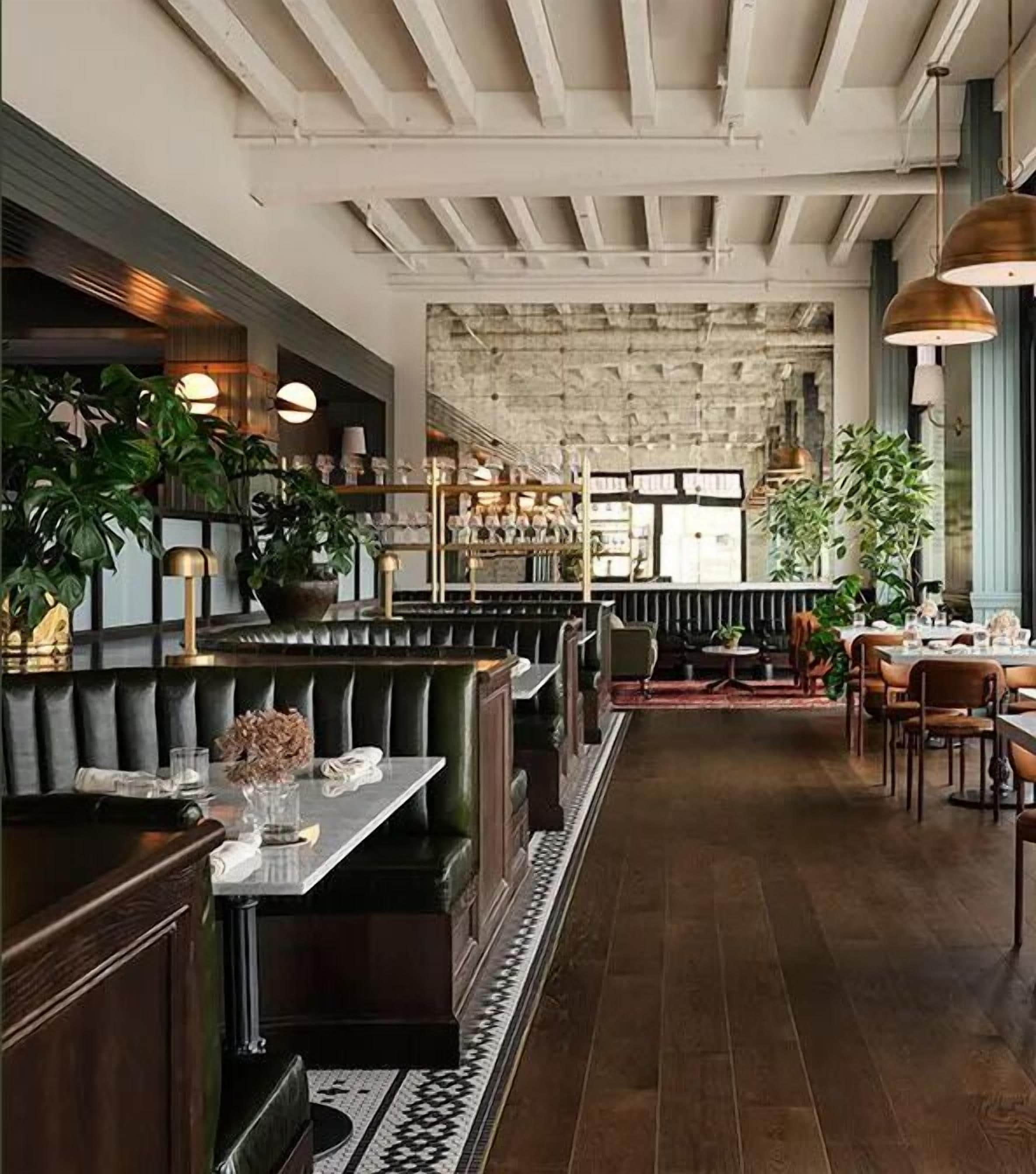 L’intérieur d’un restaurant avec des lambris en bois foncé, des banquettes en cuir et un mur en pierre en arrière-plan.