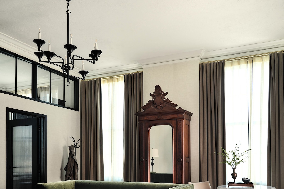 Una sala de estar moderna con un sofá verde, un sillón negro, una mesa de centro y un espejo grande.
