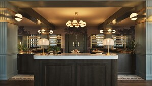 A bar area with a central island, two chandeliers, and shelves with glassware. - Hotel 1928 (Waco)