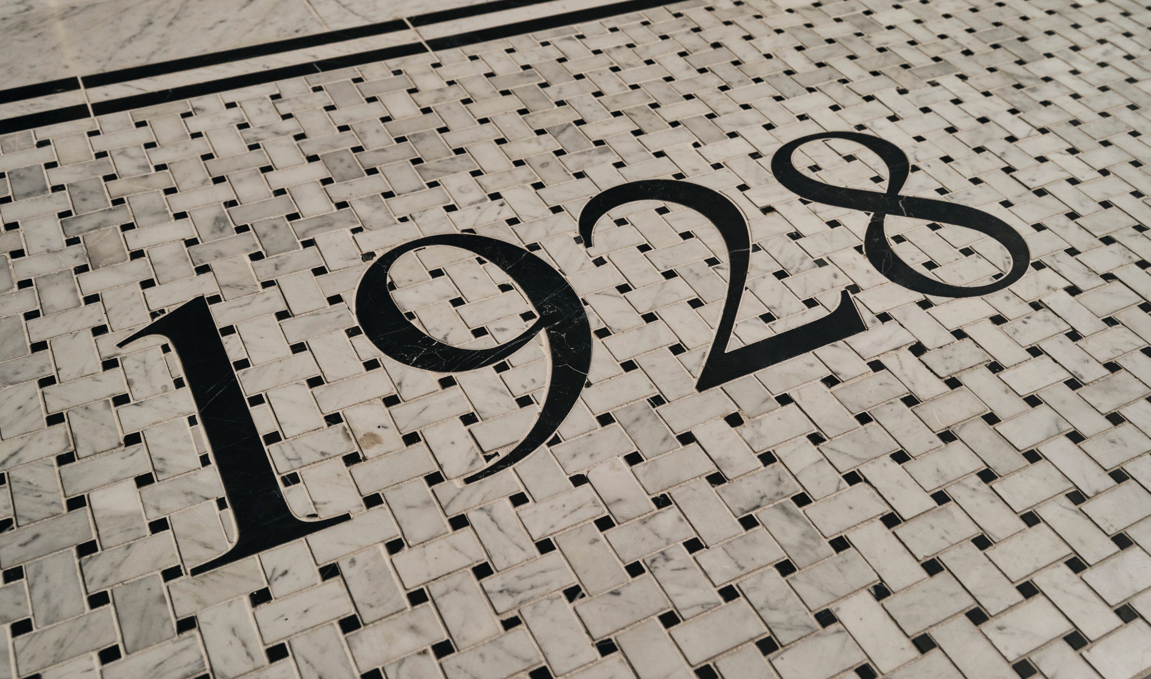Piso de azulejos com o ano '1928' gravado em letras pretas grandes.