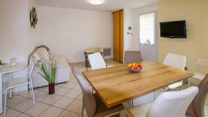 A dining area with a wooden table, white chairs, a small potted plant, and a bowl of fruit. - Lovely home in Chassiers (Chassiers)