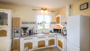 A compact kitchen with white cabinets, a microwave, a coffee maker, and a sink. - Lovely home in Chassiers (Chassiers)