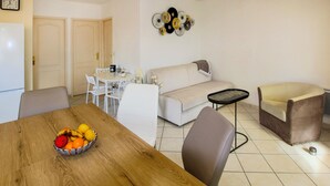 A compact living space with a dining area, a sofa, a small table, and a fruit bowl on a wooden table. - Lovely home in Chassiers (Chassiers)