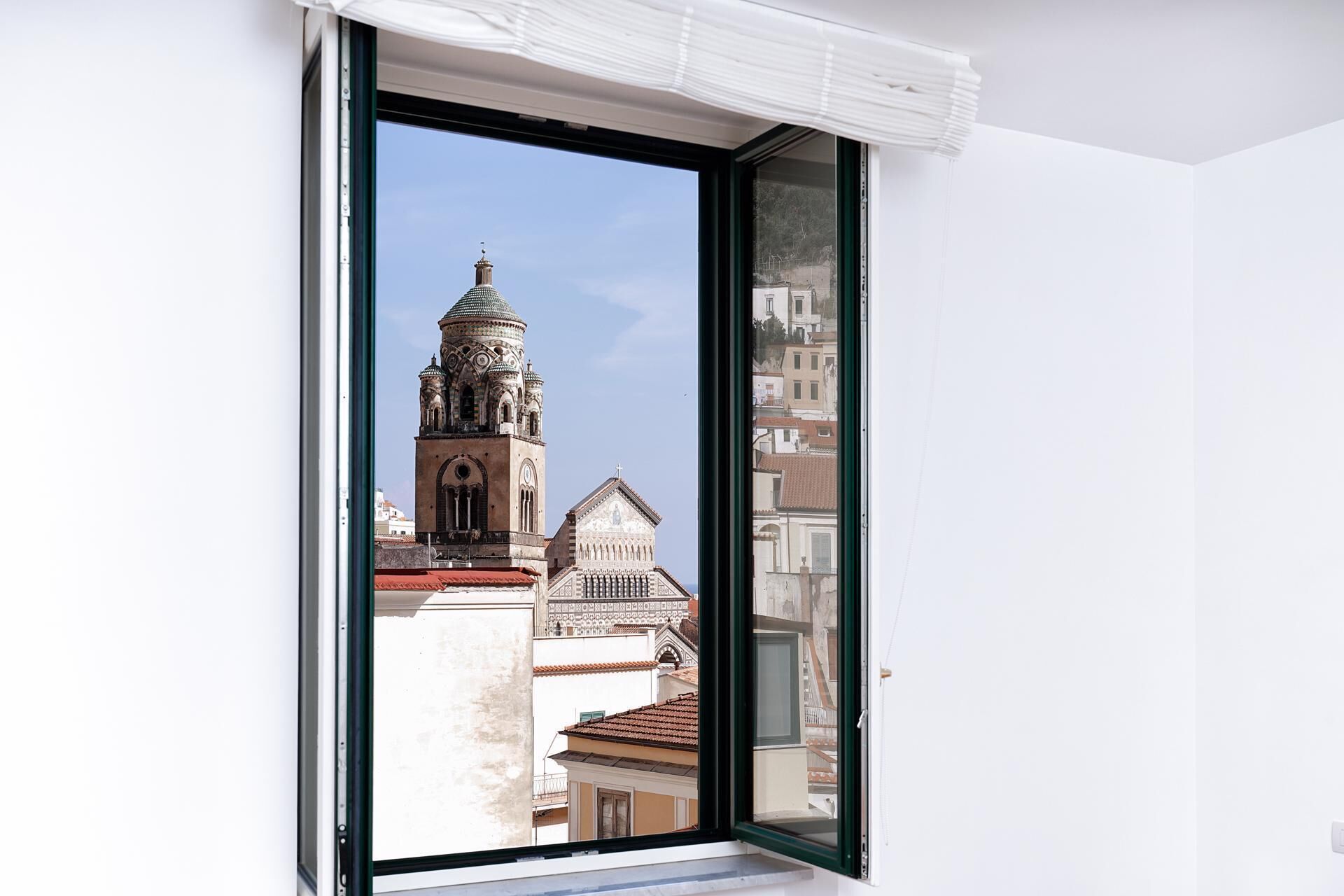 Ein Fenster mit Blick auf ein historisches Gebäude mit Glockenturm und Kuppel.