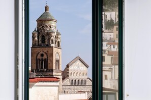A view of a historic building with a prominent tower and a smaller adjacent structure, through a window. - Francesca Flat   Amalfi (SA)