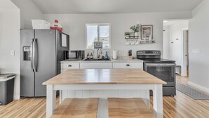 Une cuisine moderne équipée d’un réfrigérateur en acier inoxydable, d’un four à micro-ondes, d’un évier et d’une table à manger en bois.