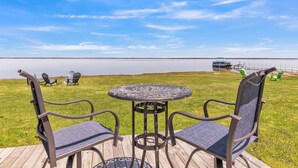 Une terrasse avec deux chaises et une table, donnant sur une étendue d’eau calme.