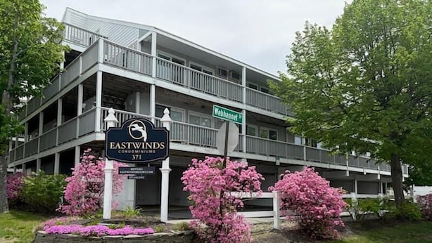 A multi-story building with a sign for Eastwinds Condominiums at 371 Webhannet St. - Located just steps from Wells Beach, Eastwinds 124 is perfect for your getaway. (Wells)