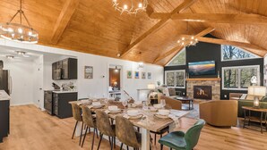 A spacious living area with a high ceiling, a fireplace, and a dining table set for six. - 6BR Designer Home in Massanutten with Hot Tub, Sauna (McGaheysville)