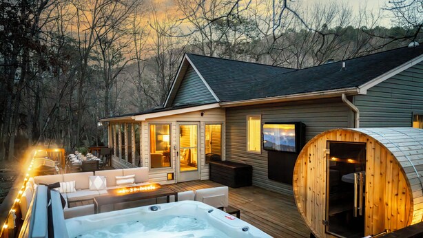A wooden deck with a hot tub, outdoor seating, and a wooden sauna. - 6BR Designer Home in Massanutten with Hot Tub, Sauna (McGaheysville)