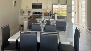 A modern kitchen with white cabinets, stainless steel appliances, and a central island with seating. - Charming 3-bedroom townhome with WiFi, AC in Reunion Resort, Kissimmee, FL
 (Kissimmee)
