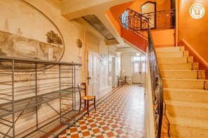 Staircase leads to a beautifully decorated corridor with a checkered floor and a mural-adorned wall.