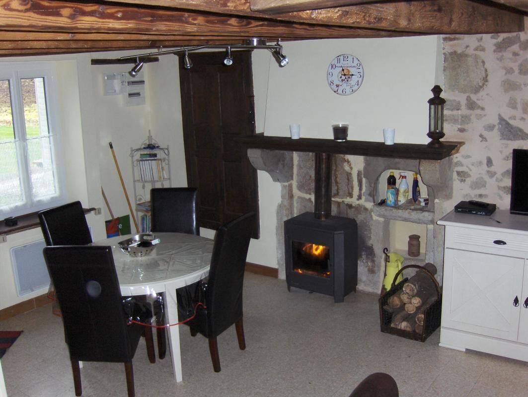 A cozy room with a stone fireplace, a dining table with chairs, and a white cabinet.