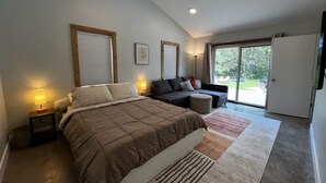 A bedroom with a bed, a sofa, a desk, and a window. - The North Oak, a Modern Cabin (Washburn)