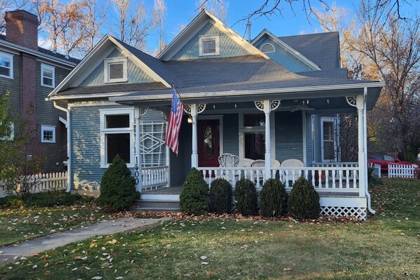 Une maison à deux étages avec un porche, un drapeau et une clôture en piquets.