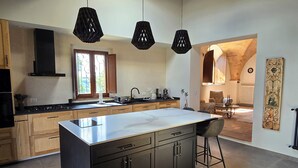 Une cuisine moderne dotée d’un grand îlot central, de meubles en bois et de luminaires suspendus.