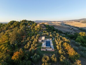 A residential property with a swimming pool, surrounded by dense vegetation and hills in the background.
