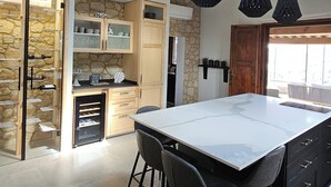 Une cuisine moderne dotée d’un grand îlot central, de meubles en bois et de luminaires suspendus.