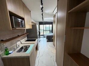 A compact kitchen with a microwave, sink, and countertop. - Haus Mitre Residences (São Paulo)