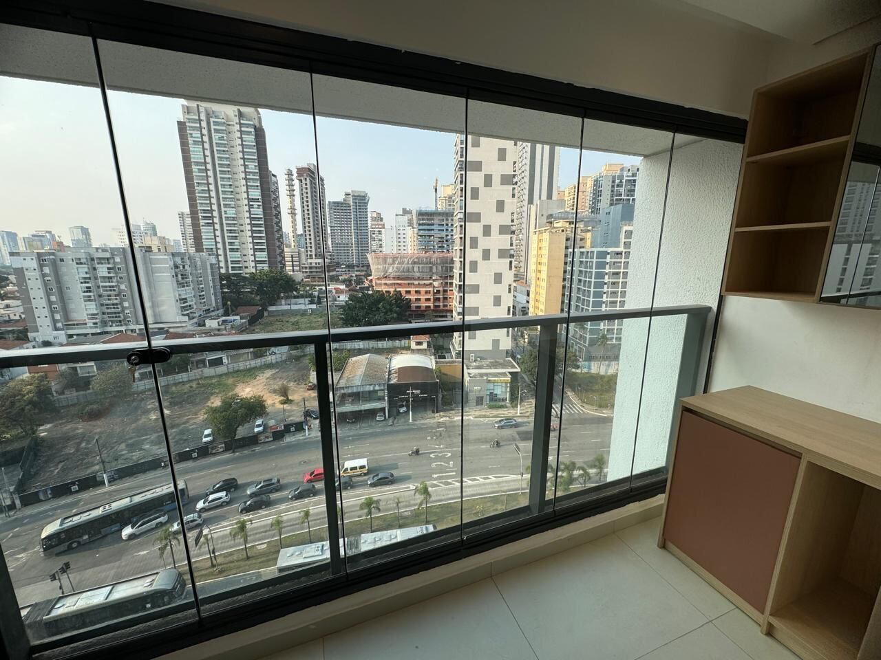 A room with a large window offering a view of a cityscape with tall buildings and a busy street.
