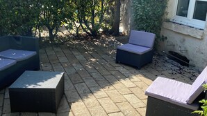 Een terras met rieten meubilair en een tegelvloer.
