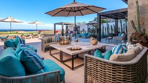 A patio area with outdoor seating, umbrellas, and a view of the ocean. - Quivira/Cabo Golf Course Villa W/Awesome OceanView, Infinity Pool on Fairway 18  (Cabo San Lucas)