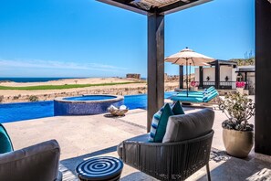 Un espace piscine doté d’un jacuzzi, de chaises longues et offrant une vue sur la plage.