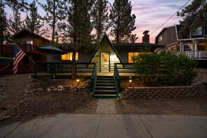 A cabin with a front porch, a staircase, and a flag.