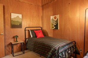 Une chambre à coucher comprenant un lit, une table de chevet, une lampe et deux œuvres d’art murales.
