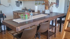 Una cocina de madera con una isla central, dos taburetes de bar y un colgador para cuchillos.