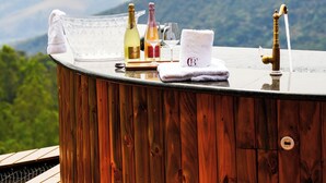 Een houten bar met uitzicht op bergen, een champagnefles, een wijnglas en een handdoek.