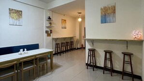 A spacious room with a dining table, multiple stools, and a ceiling fan. - Yilan Hall 2 (Jincheng)