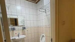 A small, tiled bathroom with a sink, toilet, and mirror. - Yilan Hall 2 (Jincheng)