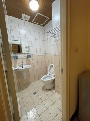 A compact bathroom with a pedestal sink, toilet, and towel rack.