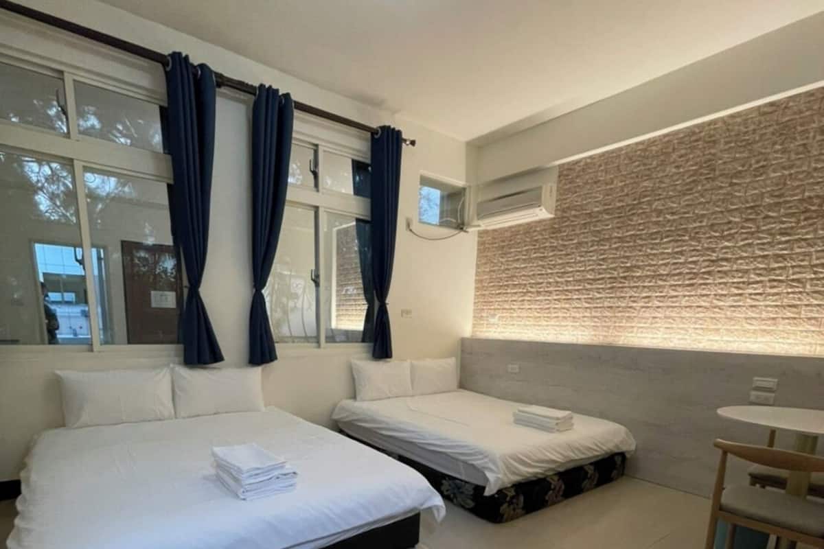 Una habitación de hotel moderna con dos camas, una mesita y un ventanal con cortinas.