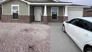 A two-story house with a front porch, a garage, and a driveway.