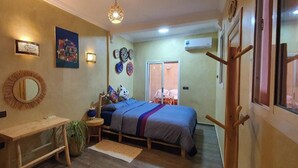 Un dormitorio con cama, mesita de noche y espejo. Hay una puerta que da a otra habitación.