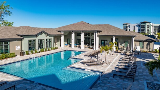 A swimming pool with lounge chairs and a covered patio area. - Landing Palmetto Apartments (Palmetto)