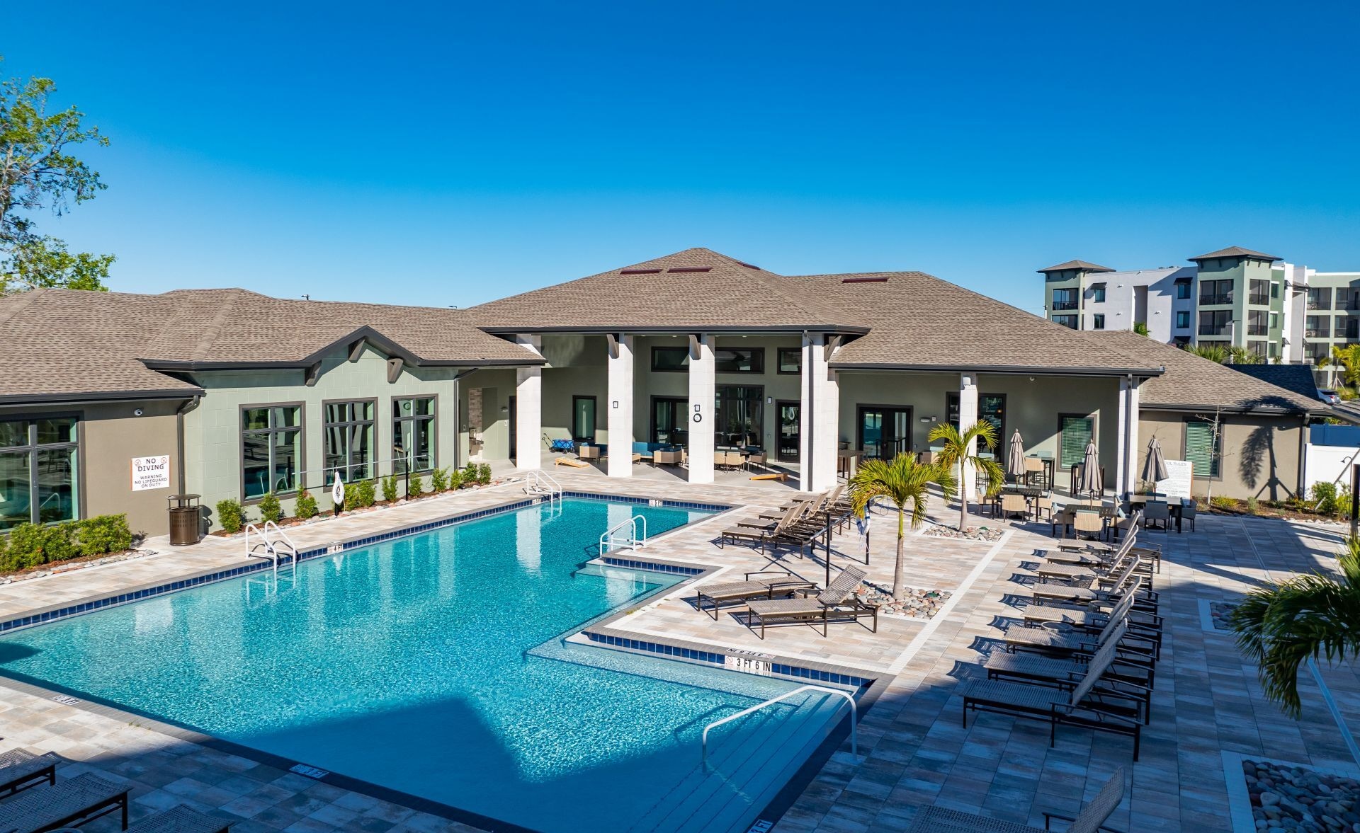 Une piscine avec des chaises longues et un espace patio couvert.