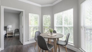 A dining area with a round table, four chairs, and a potted plant. - Landing Apartments Richmond (Richmond)