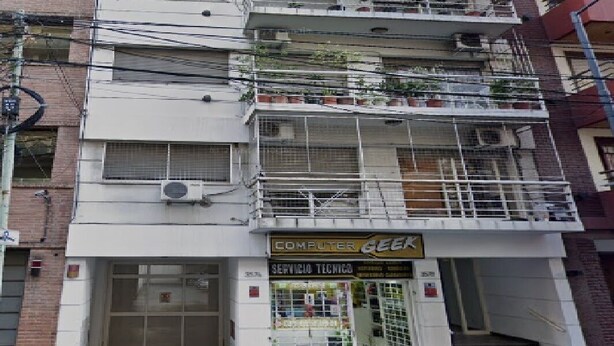 A multi-story building with a storefront labeled "COMPUTER GEEK" on the ground floor, featuring a service technical sign.