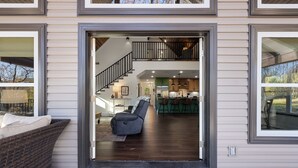 Un intérieur moderne avec un escalier menant à un étage supérieur, un coin cuisine et un espace salon comprenant un canapé et des fauteuils.