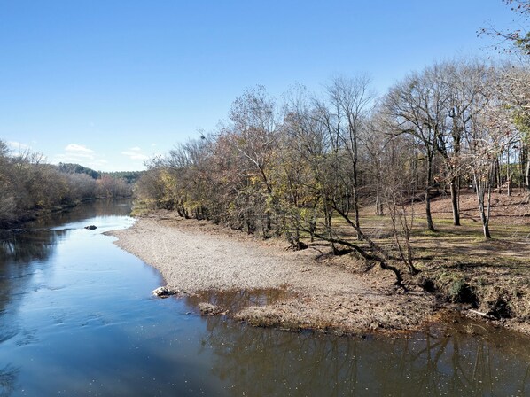 A riverbank with trees and a clear sky.