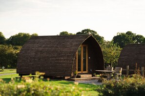 Une cabane en bois avec un toit incurvé, une porte et une petite véranda avec une table et des chaises.